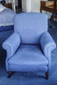 A blue upholstered armchair on turned legs