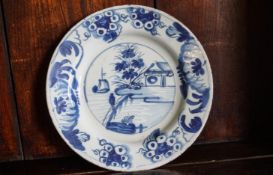 An 18th century English Delft plate, painted with a figure and flower branches,