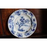 An 18th century English Delft plate, painted with a figure and flower branches,