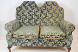 A Queen Anne style sofa with double arched back and two loose cushions, on cabriole legs,