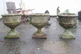 A group of three composite stone garden urns, of octagonal form,