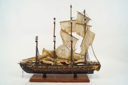 A wooden model of a four masted battleship, set with three decks of cannons,