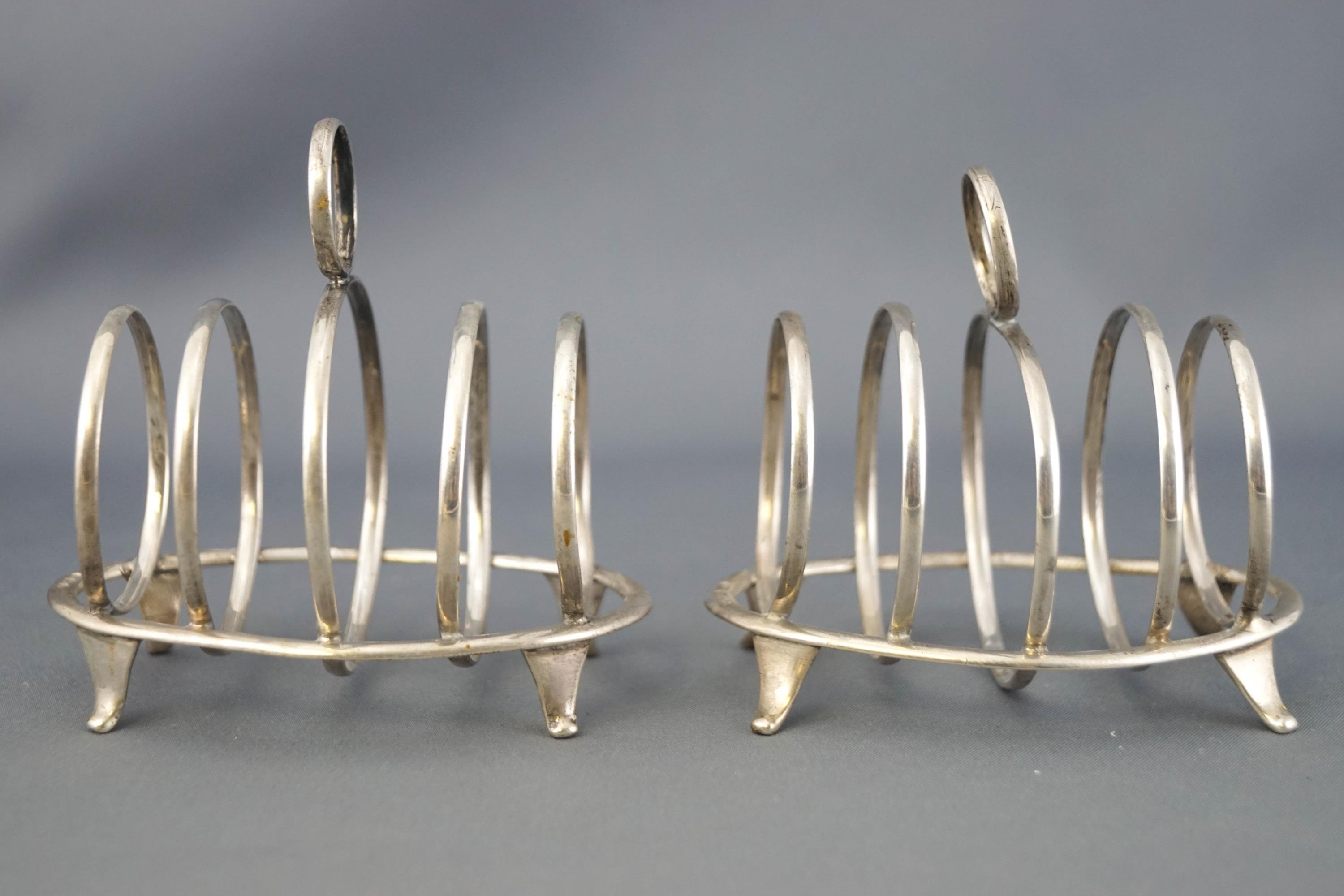 A pair of small silver four slice toast racks, with round handles and dividers,