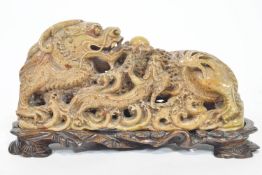 A Chinese carved soapstone figure of the dragon chasing the pearl with another, on a foamy sea,