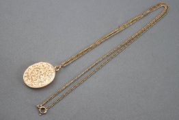 A yellow metal oval locket with engraved finish suspended from a curb link chain.