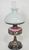 An opaline glass and brass oil lamp with a white glass shade over a graduated pink reservoir,