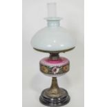 An opaline glass and brass oil lamp with a white glass shade over a graduated pink reservoir,