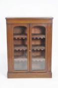 A Victorian mahogany standing bookcase with two arched glazed doors on plinth base,