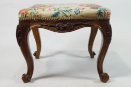 A Victorian stool on carved cabriole legs with scroll feet,