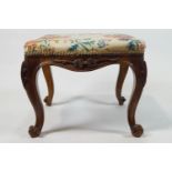 A Victorian stool on carved cabriole legs with scroll feet,