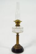 A brass oil lamp with cut glass reservoir on a ribbed brass column on a black glazed terracotta base