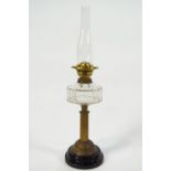 A brass oil lamp with cut glass reservoir on a ribbed brass column on a black glazed terracotta base