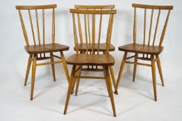 A set of four light wood and elm Ercol stick back chairs with plain back rail,