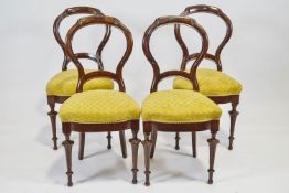 A set of four mahogany chairs with carved and shaped balloon backs on stuff over seats