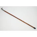 A walking cane, the metal knop being a mailed fist holding a baton,