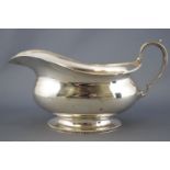 A silver sauce boat, of bellied oval form with milled edging and C scroll handle, Birmingham 1932,