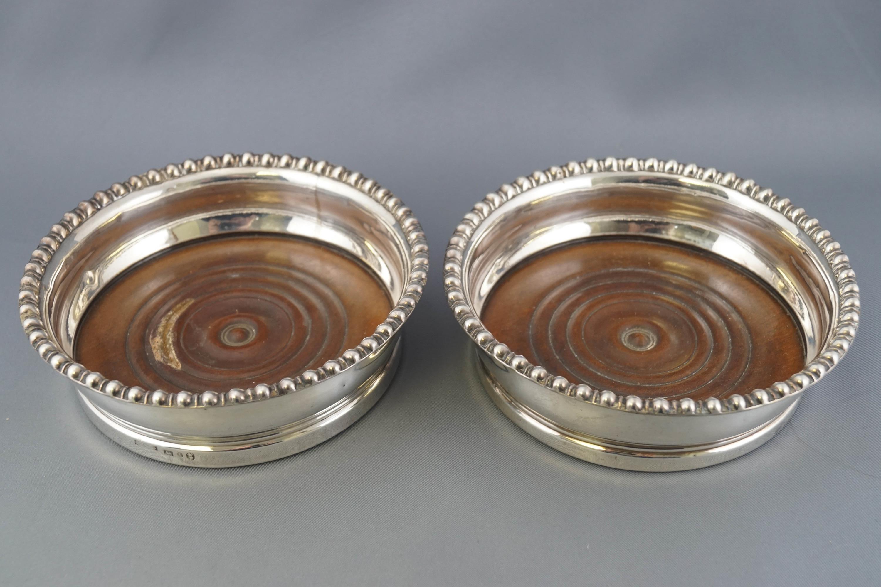 A pair of silver wine coasters with gadrooned edges over bellied bodies on turned hardwood bases, - Image 2 of 3