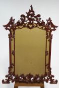 A wall mirror in George III Rococo style frame, with C scrolls and flowers,