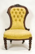 An Edwardian mahogany show frame nursing chair with button back on turned legs with brass casters,