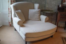 A large wing back armchair with long deep seat on square tapering legs,