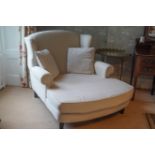 A large wing back armchair with long deep seat on square tapering legs,