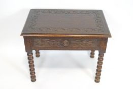 A carved dark oak side table with pull out drawer on bobbin legs,