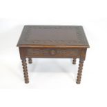 A carved dark oak side table with pull out drawer on bobbin legs,