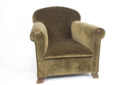 A small Howard & Sons style armchair with domed sloping back with elongated seat and scroll arms,