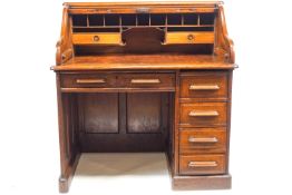 An oak roll top desk of small proportions, the top opening to reveal pigeonholes and two drawers,
