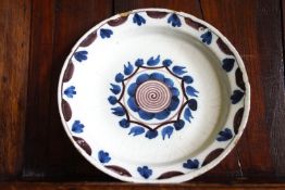An 18th century English Delft plate, the centre painted with a stylised flower head,
