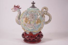 A Chinese porcelain teapot heavily decorated with moulded panels of dragons with moving eyes,