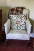 A white upholstered armchair on beech stained cabriole legs and casters