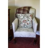 A white upholstered armchair on beech stained cabriole legs and casters