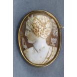 A yellow metal oval carved cameo brooch. Base metal pin and revolver fitting.