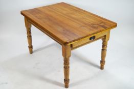 A pine table with one frieze drawer on turned legs,
