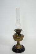 An Art Nouveau brass oil lamp with chimney and china base,