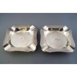 A pair of silver ashtrays of shaped cut corner form with all over engine turned decoration,