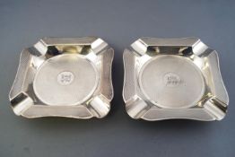 A pair of silver ashtrays of shaped cut corner form with all over engine turned decoration,