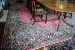 A large woven carpet the central medallion on a pink field with flower decorated spandrels within