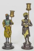 Two cold painted metal figural candlesticks in the form of a male and female Moor, in exotic dress,