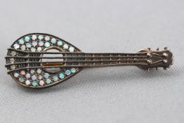A yellow and white metal guitar brooch set with small cabochon cut opals and round cut diamonds.