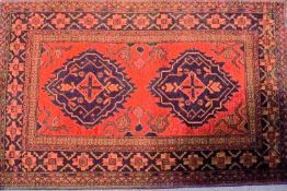 A Turkoman rug with two medallions on a red field within three borders,
