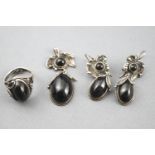 A white metal jewellery suite consisting of a ring, pendant and earrings,