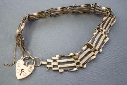 A yellow metal four bar twisted and plain gate bracelet. Padlock and safety chain fittings.