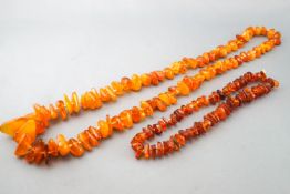 A collection of two strands of graduated orange beaded necklaces.