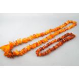 A collection of two strands of graduated orange beaded necklaces.