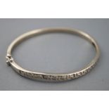 A white metal hinged bangle with cut out Greek key design.