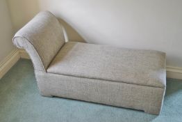 A green upholstered ottoman with raised back,