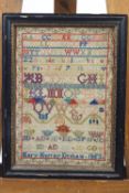 A mid 19th century framed sampler, worked in polychrome wools with sample letters and numbers,