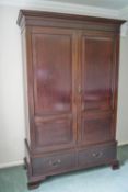 A mahogany wardrobe with two chamfered panels above two drawers on ogee bracket feet,